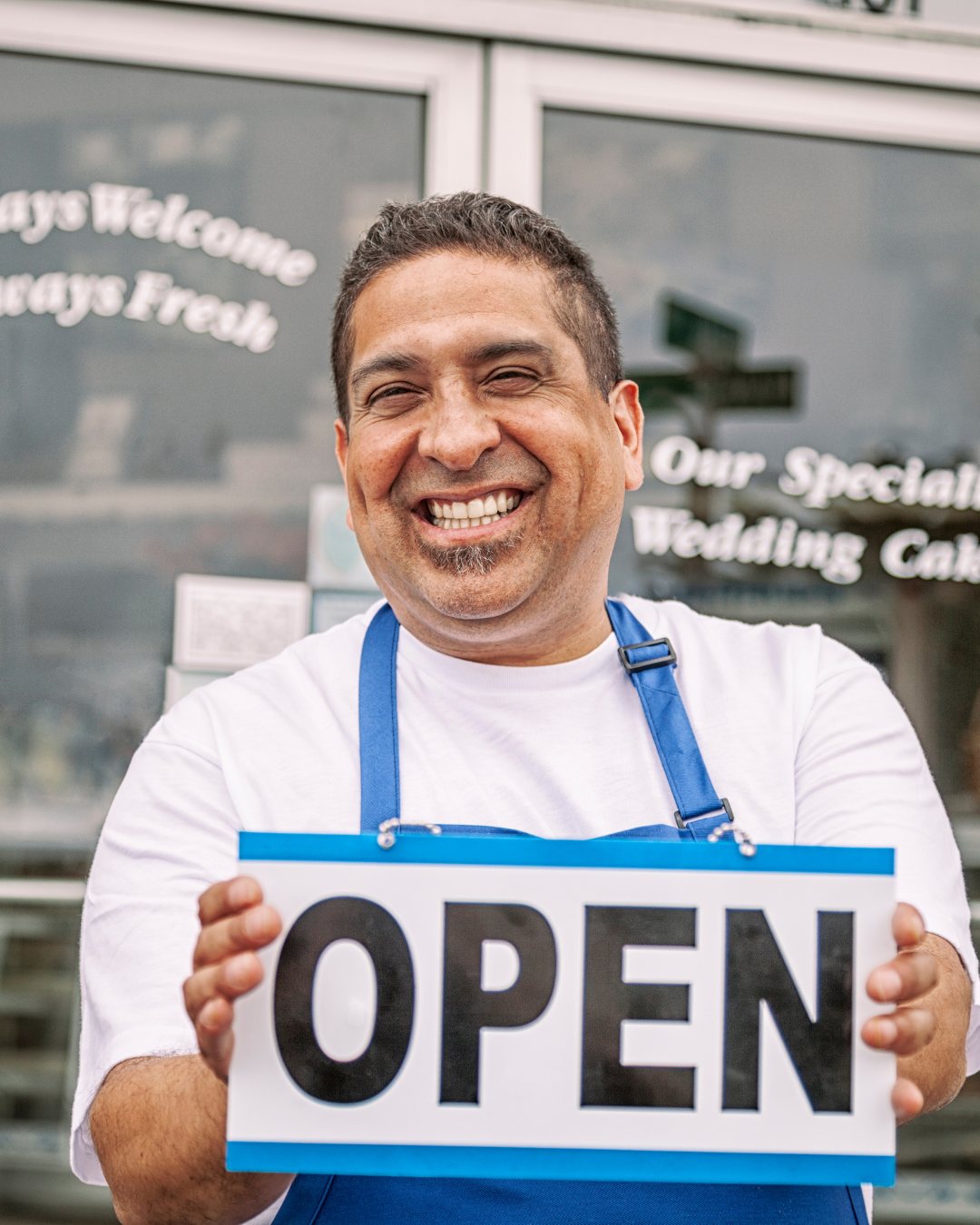 Small business owner holding an OPEN sign